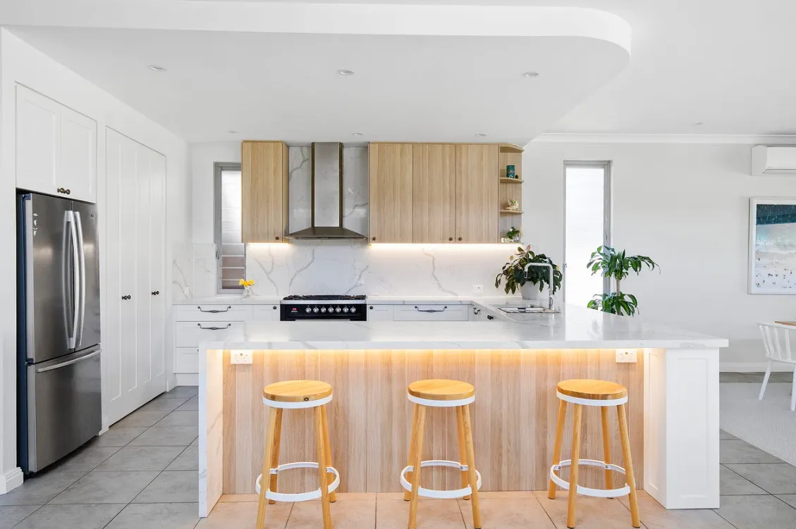 Modern kitchen with white island, bar stools and open shelving in the showroom